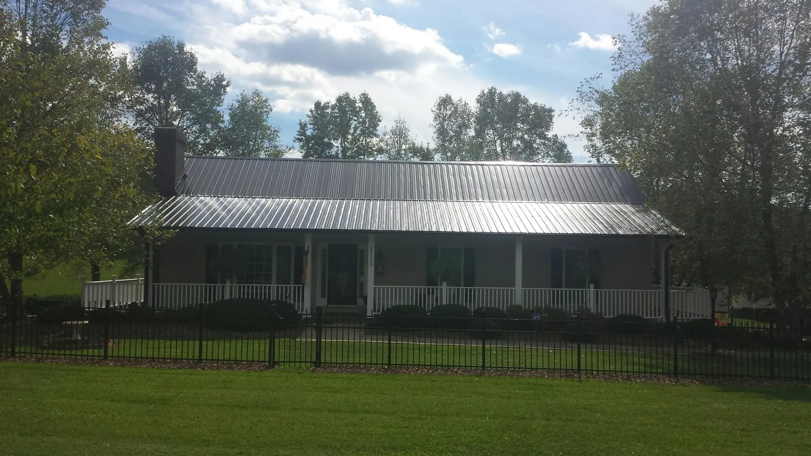 Gray metal roof on a brick ranch with a full width front porch — Gutter Guard Installation work by our crew in Vienna